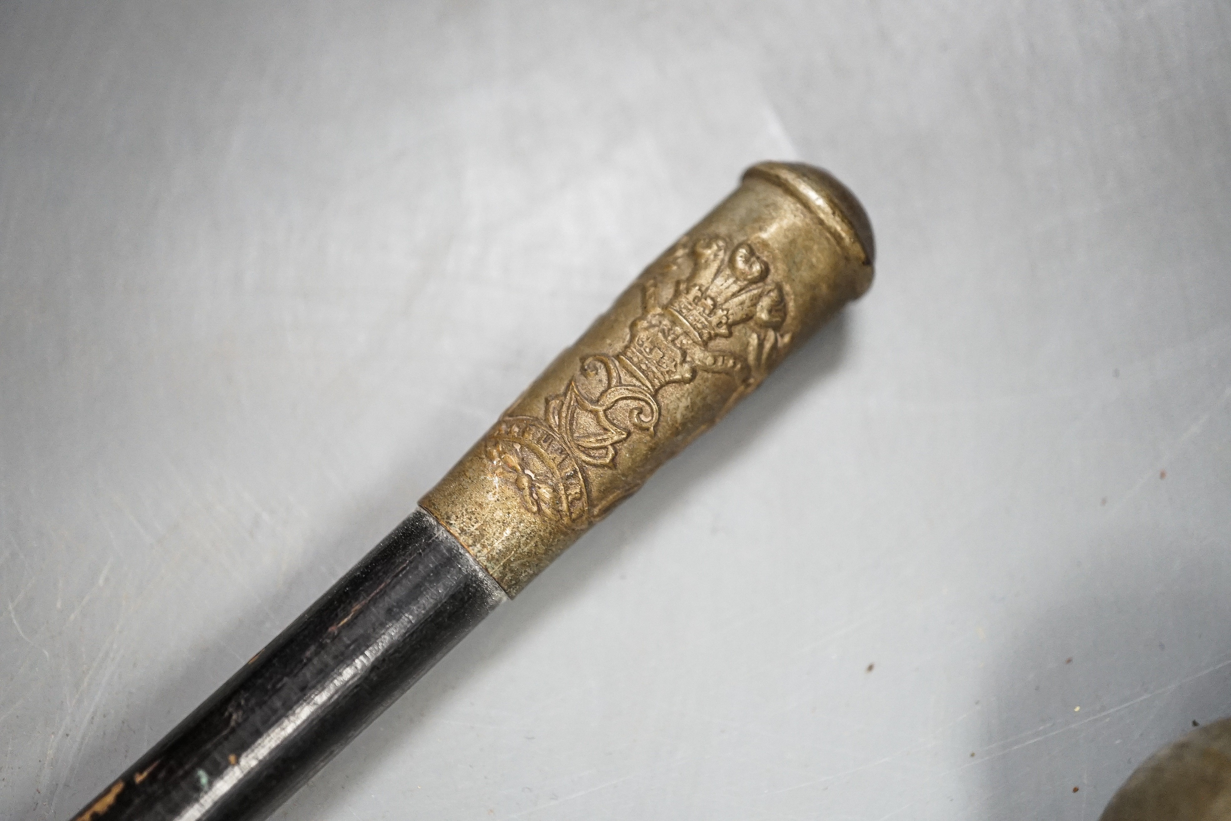 A group of WWI and WWII militaria badges, buttons, two swagger sticks, an armband and a World War I German POW inscribed plaster ornament, longest swagger stick 70 cms long.
